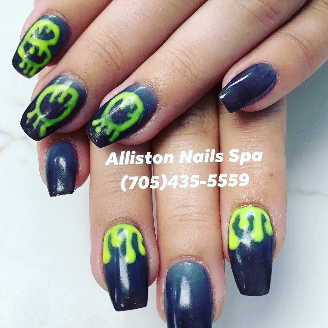 Creative nail art with neon green skull designs on dark base